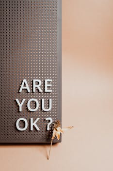 pexels-photo-7005409-7005409 Vertical shot of 'Are You OK?' text on pin board with a dried flower.
